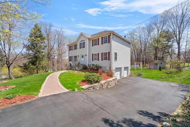 colonial house featuring a front lawn, driveway, and a garage
