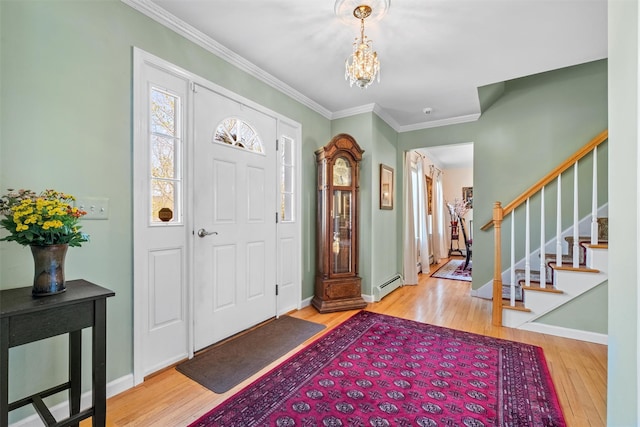 foyer with crown molding, stairway, a chandelier, a baseboard heating unit, and wood finished floors