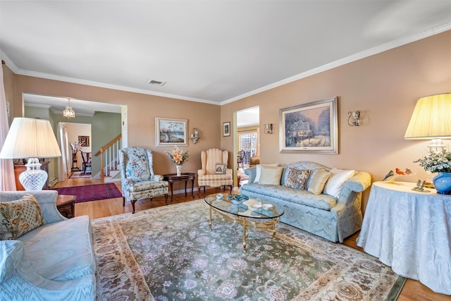 living area featuring ornamental molding, visible vents, stairway, and wood finished floors