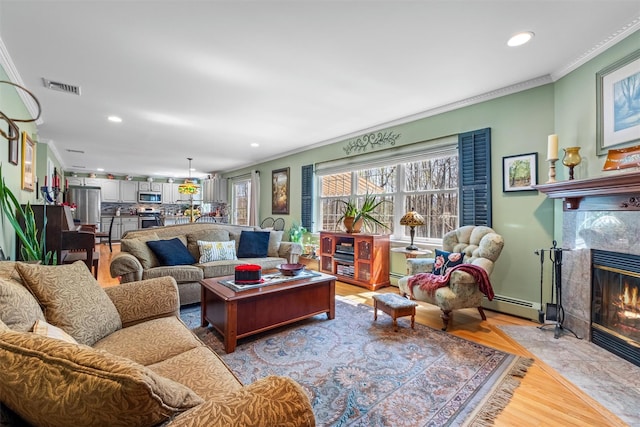 living area with visible vents, crown molding, a baseboard heating unit, and recessed lighting