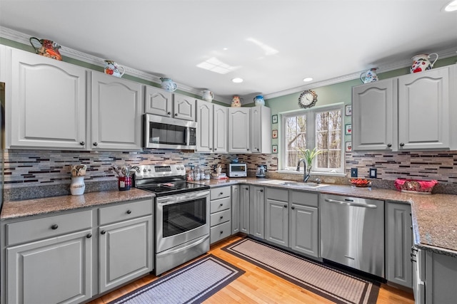 kitchen with backsplash, a sink, appliances with stainless steel finishes, and gray cabinets