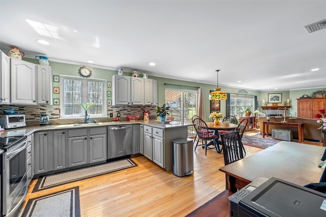 kitchen with gray cabinetry, visible vents, stainless steel appliances, and ornamental molding