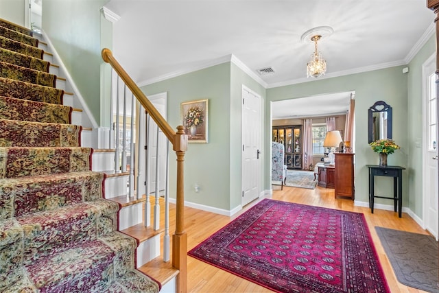 entrance foyer with wood finished floors, crown molding, and stairs