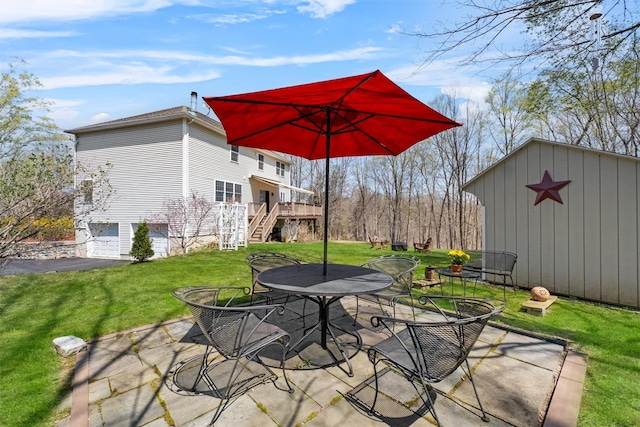 view of patio with an outdoor structure, outdoor dining area, a storage shed, an attached garage, and stairway