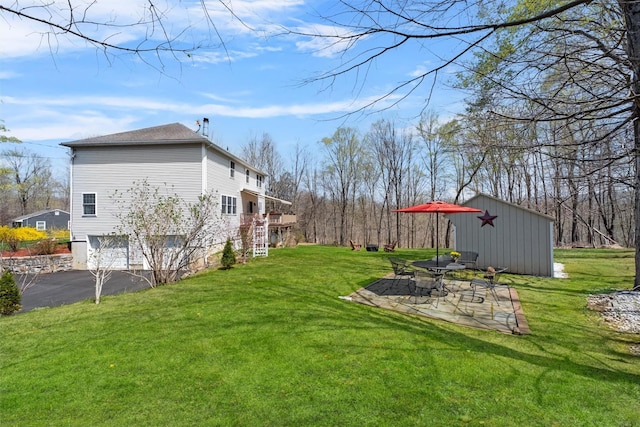 view of yard featuring driveway, a patio area, and an attached garage