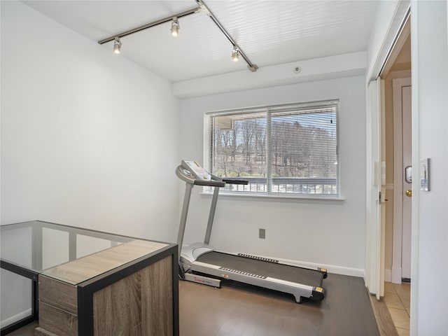 workout room with rail lighting, light wood finished floors, and baseboards