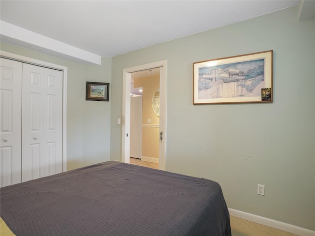 bedroom with a closet, light colored carpet, and baseboards