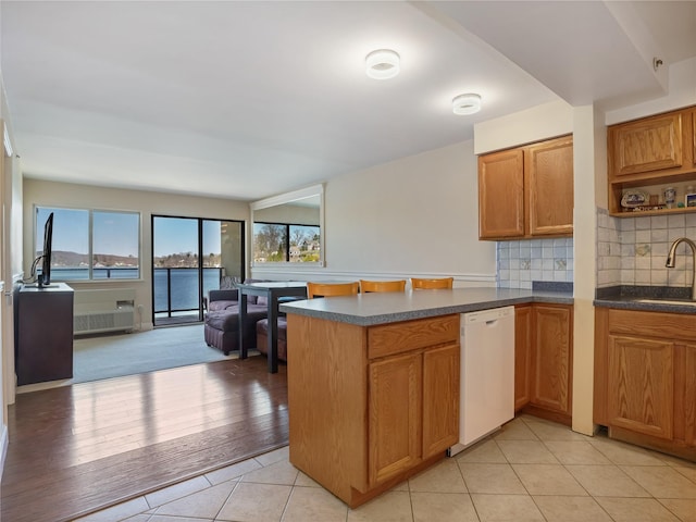 kitchen with open floor plan, a peninsula, decorative backsplash, dishwasher, and a sink