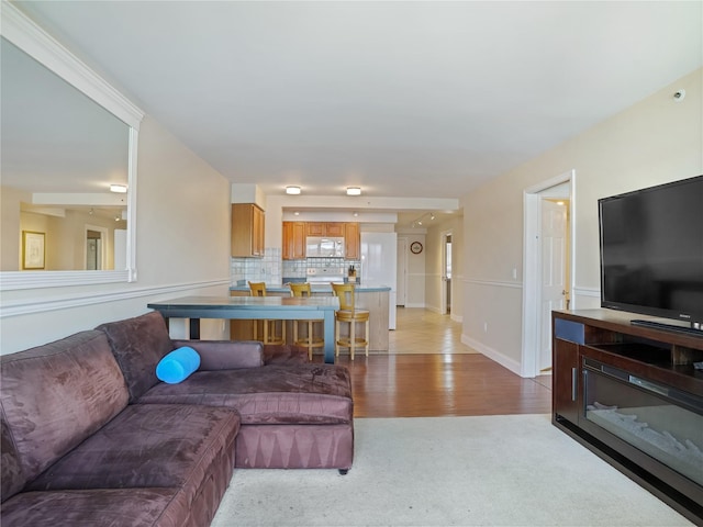 living area with light carpet, light wood-type flooring, and baseboards