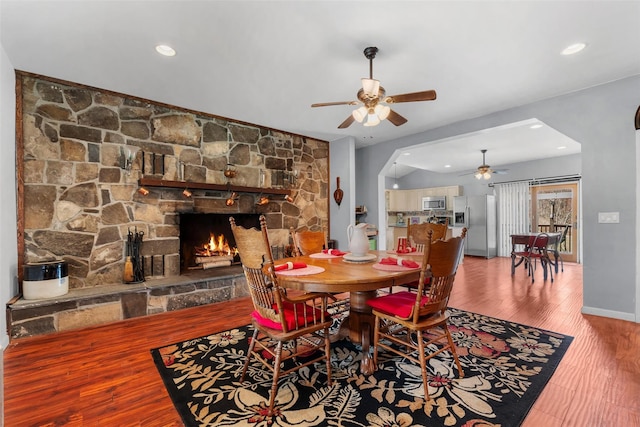 dining room with wood finished floors, a fireplace, a ceiling fan, and recessed lighting
