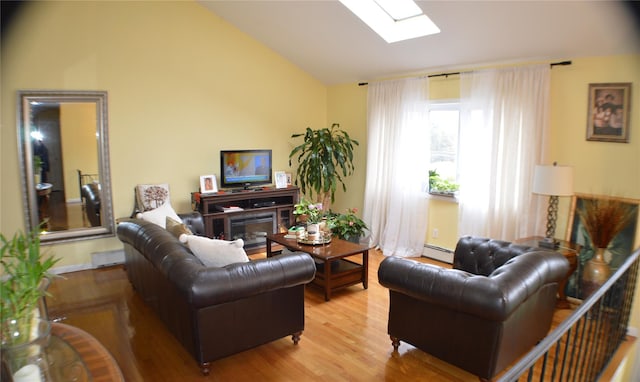 living area with a baseboard heating unit, vaulted ceiling with skylight, and light wood-style flooring