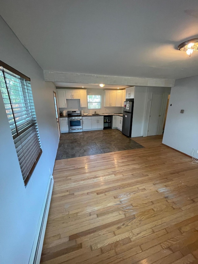 1137 Namdac Ave, Bay Shore, NY 11706 - kitchen with appliances with stainless steel finishes, white cabinets, wood finished floors, and a baseboard heating unit