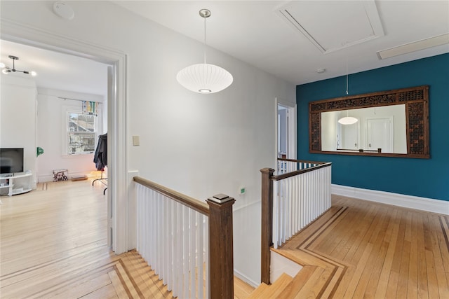 hall with attic access, hardwood / wood-style floors, and an upstairs landing