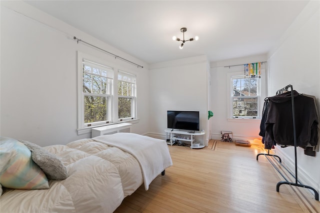 bedroom with wood-type flooring, multiple windows, and an inviting chandelier