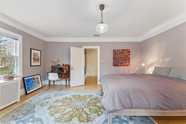 bedroom featuring visible vents, light wood finished floors, and radiator heating unit