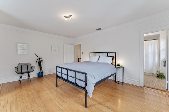 bedroom with baseboards, visible vents, and light wood finished floors