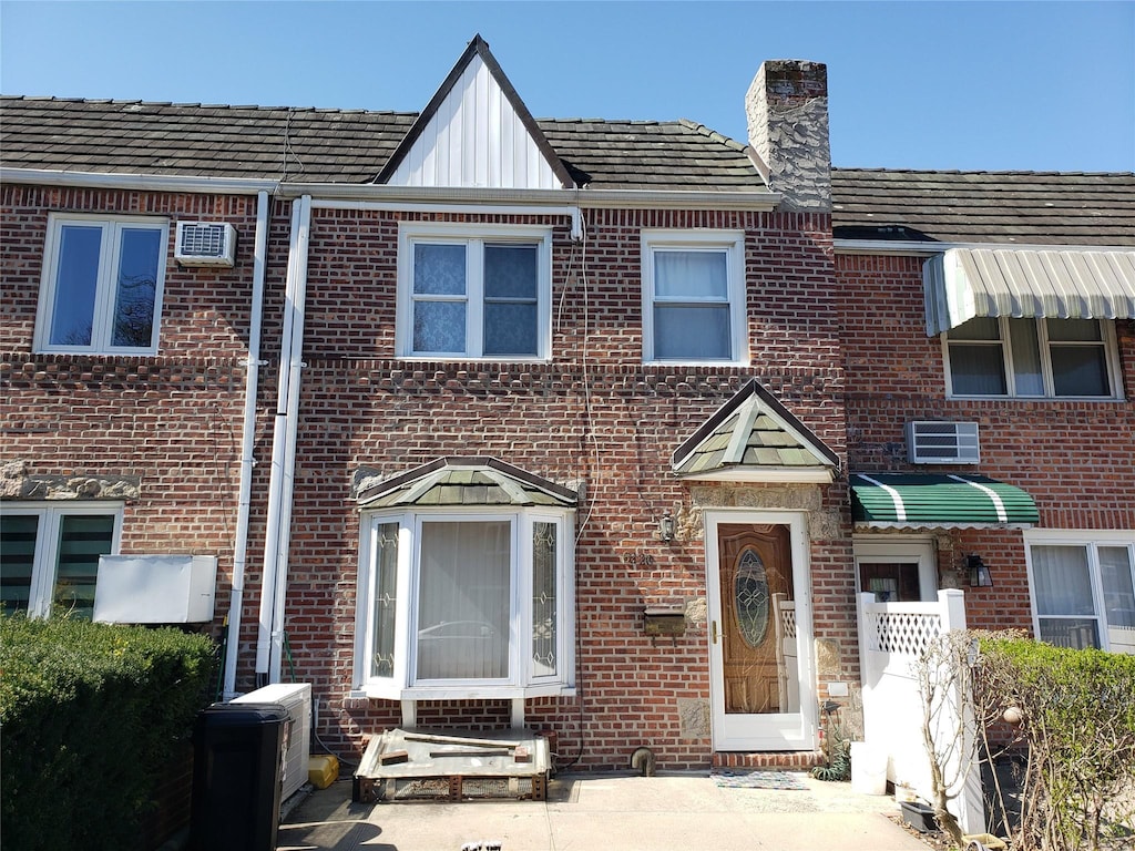 62-20 79th St, Middle Village, NY 11379 - view of property with a wall mounted air conditioner, brick siding, board and batten siding, and a chimney