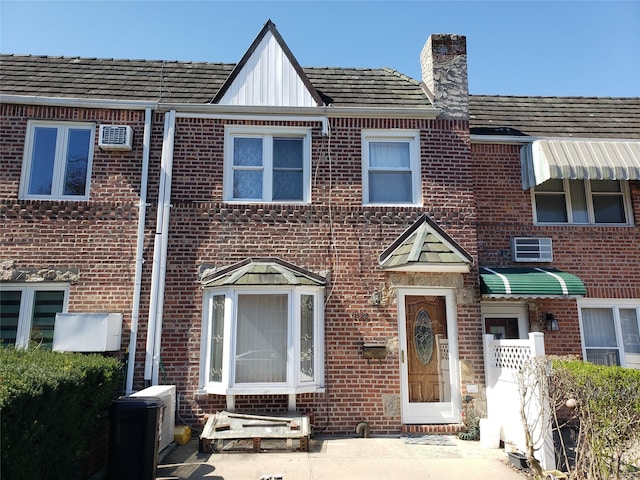 62-20 79th St, Middle Village, NY 11379 - view of property with a wall mounted air conditioner, brick siding, board and batten siding, and a chimney