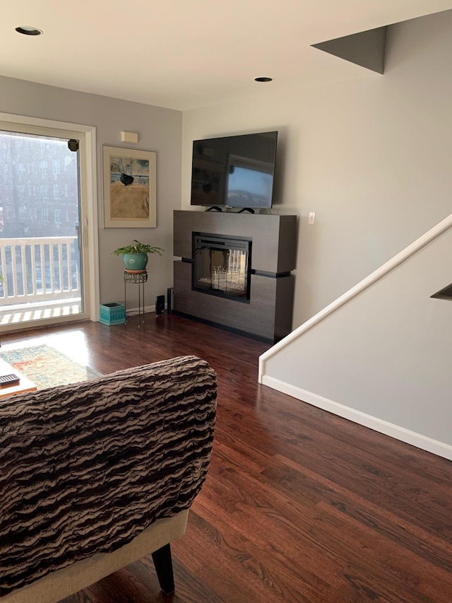 living room with wood finished floors, baseboards, a glass covered fireplace, and recessed lighting