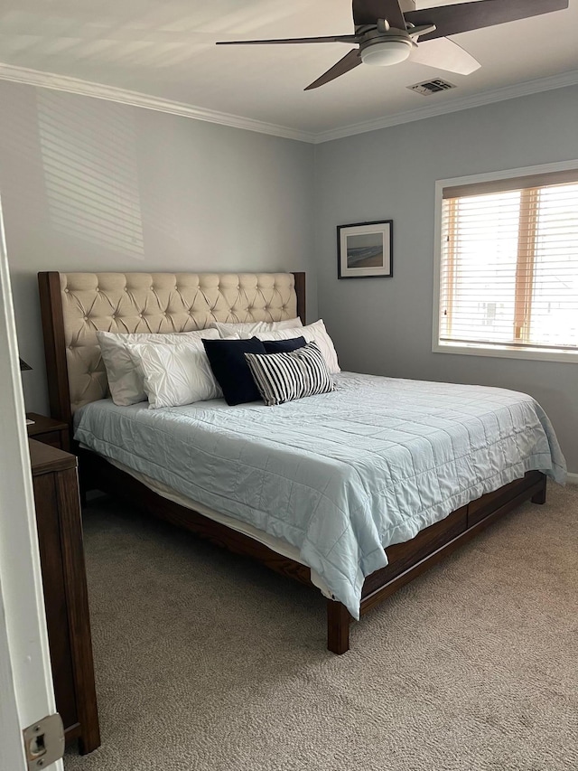 carpeted bedroom with visible vents, ornamental molding, and a ceiling fan