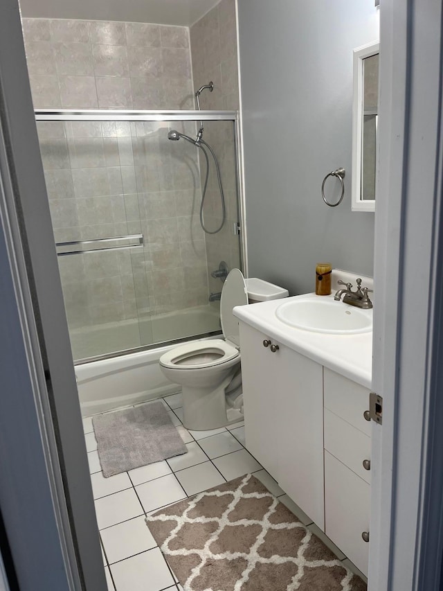 bathroom with tile patterned floors, shower / bath combination with glass door, vanity, and toilet
