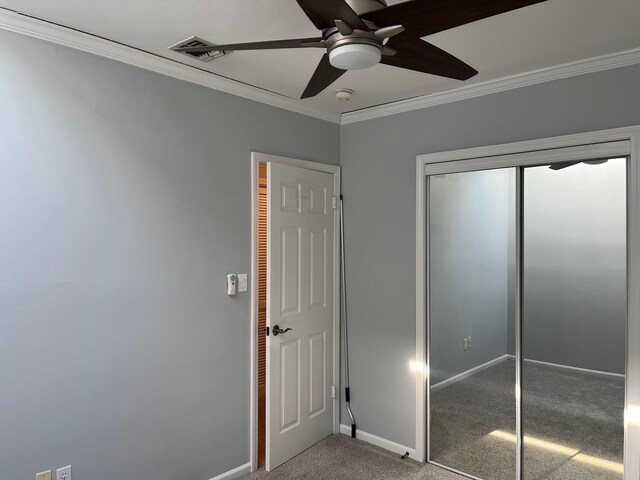 unfurnished bedroom with ceiling fan, a closet, ornamental molding, carpet flooring, and baseboards