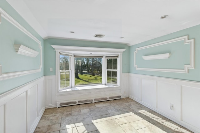 interior space with a decorative wall, visible vents, a wainscoted wall, and baseboard heating