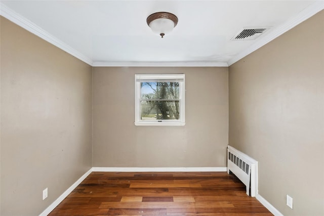 unfurnished room featuring radiator heating unit, ornamental molding, visible vents, wood finished floors, and baseboards