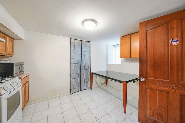 3205 Lafayette Ave, Bronx, NY 10465 - kitchen featuring stainless steel microwave, brown cabinets, light tile patterned flooring, and white gas range oven
