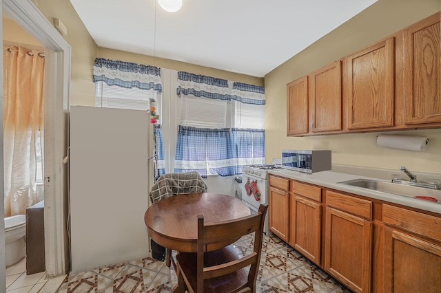 3205 Lafayette Ave, Bronx, NY 10465 - kitchen featuring light tile patterned floors, a sink, light countertops, gas range gas stove, and stainless steel microwave