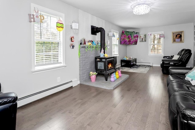 living room with a wood stove, a baseboard heating unit, wood finished floors, and baseboard heating