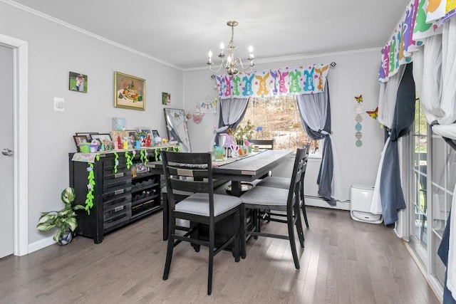 dining area with ornamental molding, a chandelier, wood finished floors, and baseboard heating