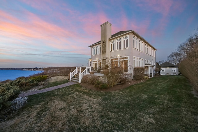 54985 Cr48, Southold, NY 11971 - back of property at dusk featuring a chimney, a water view, and a yard
