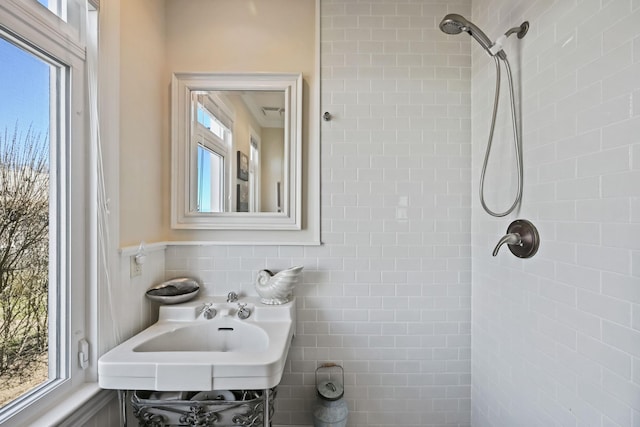 54985 Cr48, Southold, NY 11971 - bathroom featuring a tile shower, a healthy amount of sunlight, a sink, and wainscoting