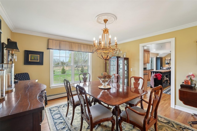 dining room featuring light wood-style flooring, ornamental molding, baseboards, and a notable chandelier