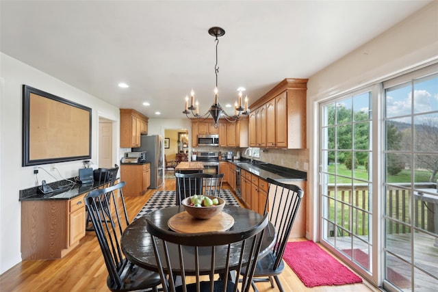 dining space with recessed lighting, a notable chandelier, and light wood-type flooring