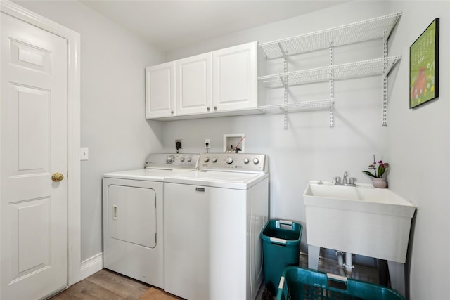 clothes washing area featuring a sink, light wood-style floors, cabinet space, washing machine and dryer, and baseboards