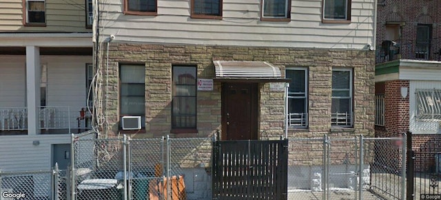 exterior space featuring stone siding, a gate, and a fenced front yard