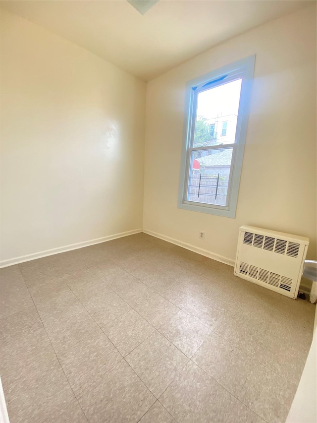 unfurnished room featuring radiator heating unit and baseboards