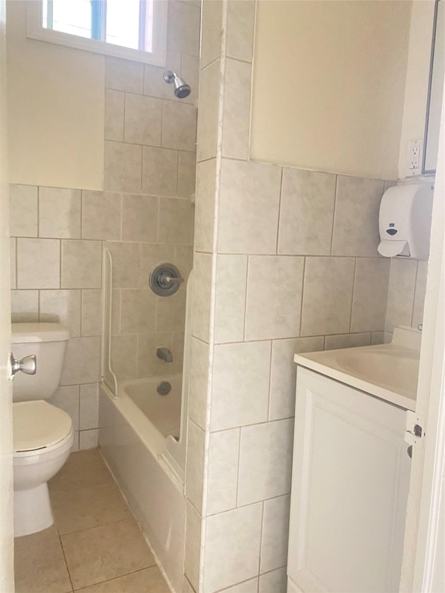 full bath with toilet, tile walls, tub / shower combination, vanity, and tile patterned floors