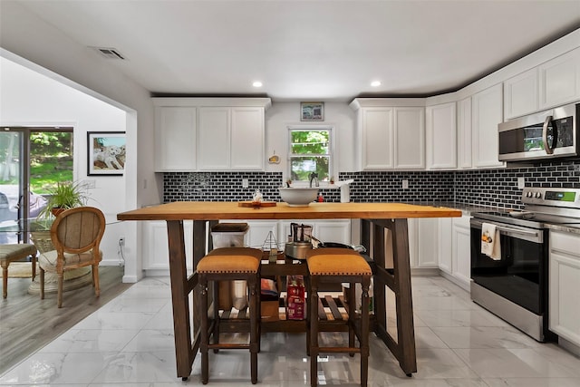 2358 Maple Ave, Cortlandt Manor, NY 10567 - kitchen with appliances with stainless steel finishes, light marble finish floors, butcher block counters, white cabinetry, and tasteful backsplash