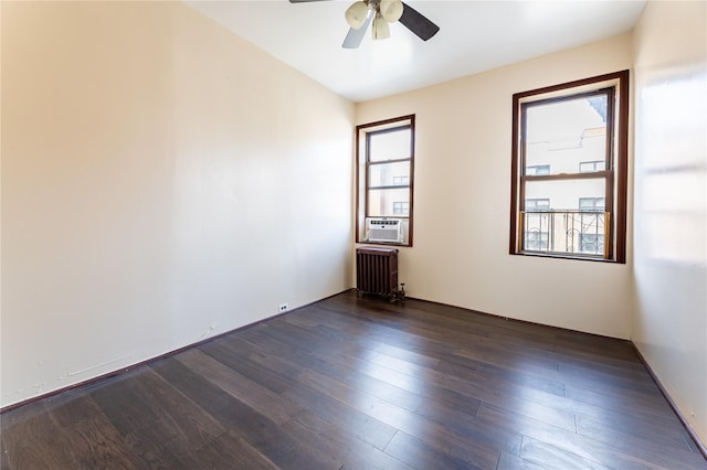 empty room featuring radiator heating unit, cooling unit, a ceiling fan, and dark wood finished floors