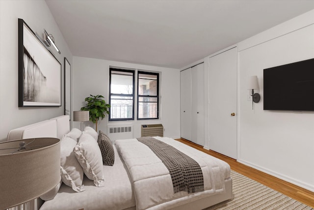 35-20 Leverich St Unit A 504, Jackson Heights, NY 11372 - bedroom with wood finished floors, two closets, radiator, an AC wall unit, and baseboards