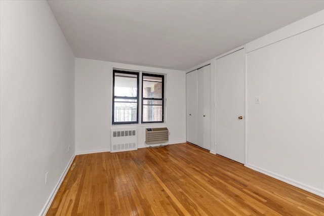 35-20 Leverich St Unit A 504, Jackson Heights, NY 11372 - unfurnished bedroom featuring a wall mounted air conditioner, multiple closets, light wood-style floors, radiator, and baseboards