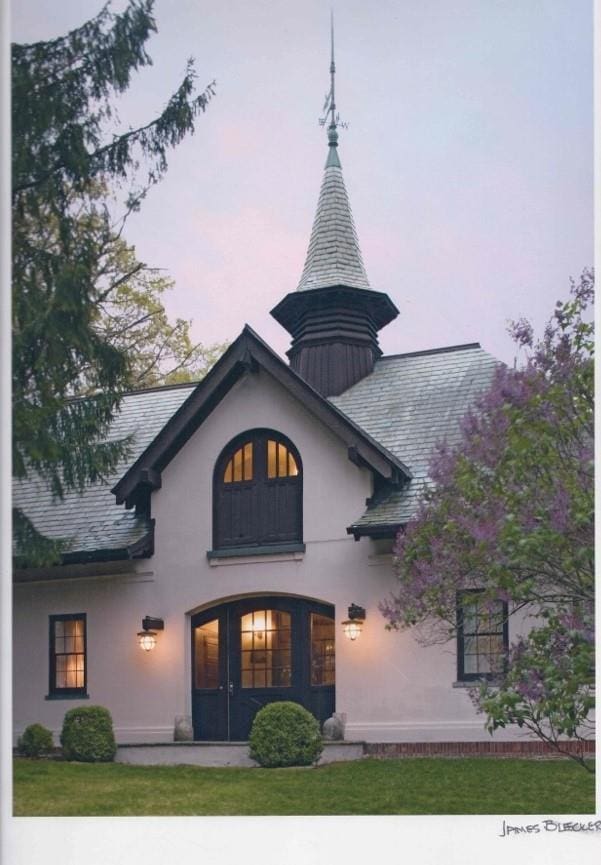 exterior entry at dusk with a yard and stucco siding