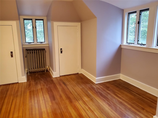 additional living space with baseboards, radiator, and hardwood / wood-style floors