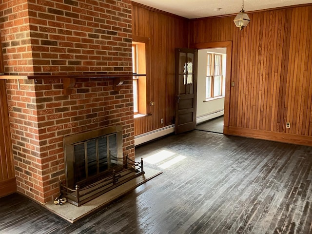 unfurnished living room with baseboard heating, wood finished floors, wood walls, and baseboards