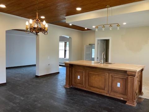 kitchen featuring a sink, brown cabinetry, recessed lighting, and arched walkways