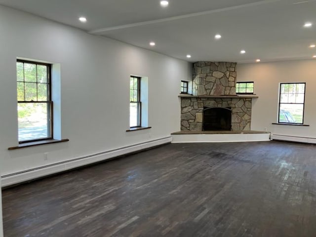 unfurnished living room featuring plenty of natural light, wood finished floors, and baseboard heating
