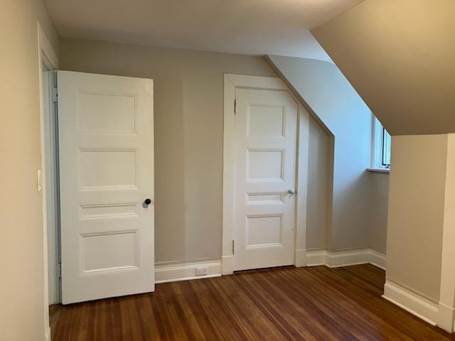 additional living space featuring dark wood-type flooring and baseboards